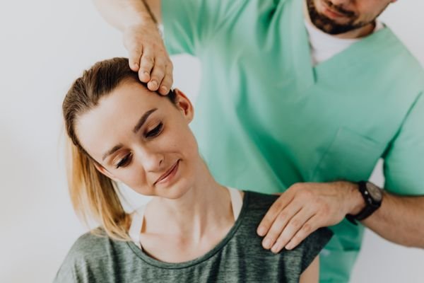 Physiotherapist treating patient's jaw and neck for TMJ dysfunction relief